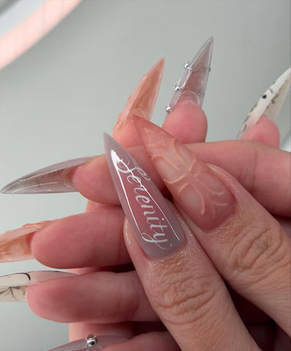 Ethereal Serenity Nude and Gray Stiletto Nails with Baroque Script and 3D Cross Design